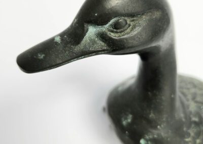 Bronze duck sculpture on white background.