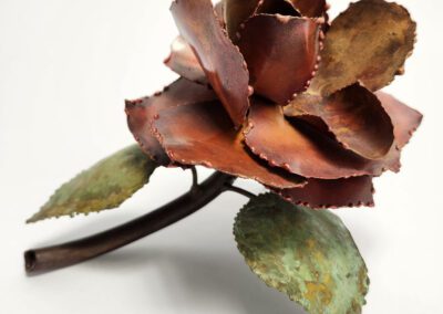 Metal flower sculpture with green leaves.