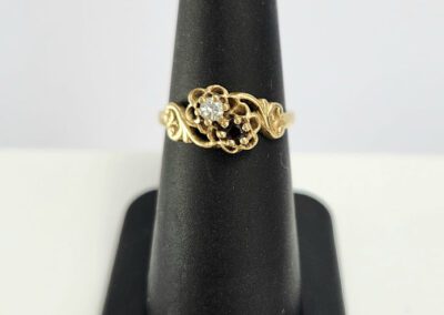 Gold ring with diamond on display stand.