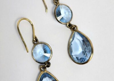 Gold earrings with blue teardrop gemstones.