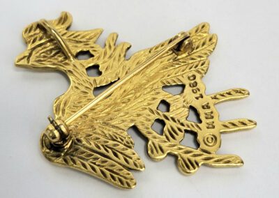 Back of ornate gold brooch with pin.