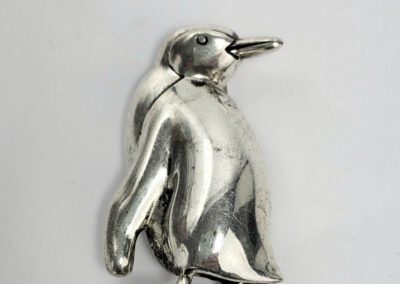 Silver penguin figurine on white background.