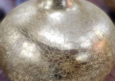 Golden vase with crackled texture on table.