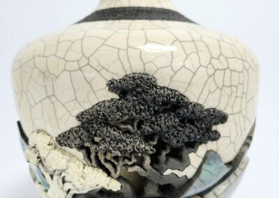 Cracked ceramic vase with intricate tree design.