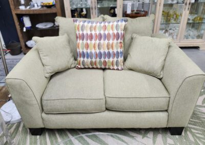Green sofa with colorful patterned pillow.
