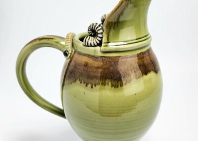 Green ceramic pitcher with decorative handle.