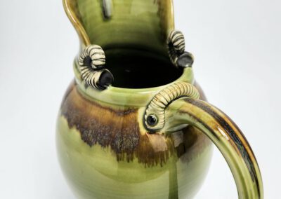 Green ceramic jug with decorative handle.