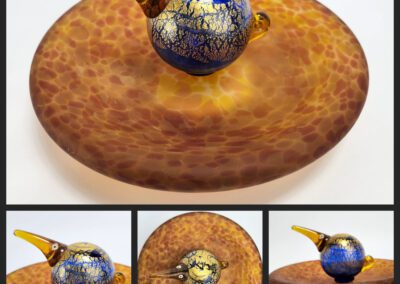 Colorful glass bird sculpture on round base.