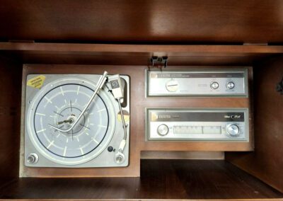 Vintage turntable and radio in wooden cabinet.