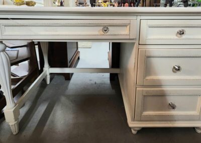 White wooden desk with drawers and knobs.