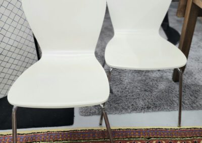 Two white chairs on patterned carpet.