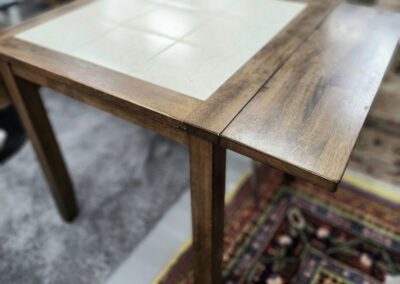 Wooden table with tiled surface and chair.