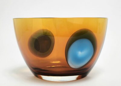 Amber glass bowl with colorful abstract design.