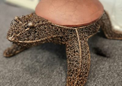 Turtle-shaped stool with intricate wire design.