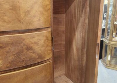 Wooden wardrobe with open door and drawers.