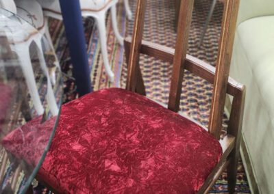 Wooden chair with red velvet cushion.