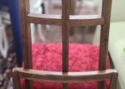 Tall wooden chair with red cushion seat.
