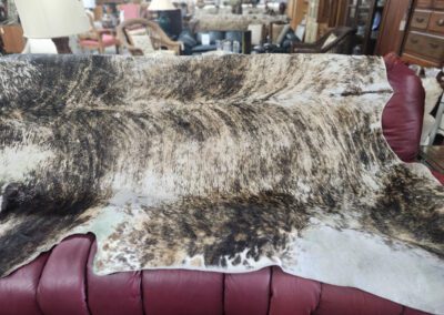 Cowhide rug draped over red sofa.
