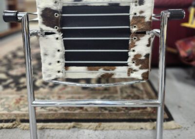 Cowhide and metal chair in room.