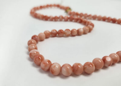 Pink coral beaded necklace on white background