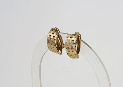 Gold woven hoop earrings on clear stand
