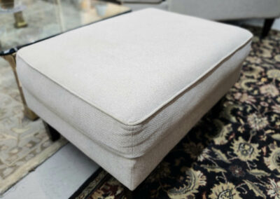 Beige upholstered ottoman on patterned rug