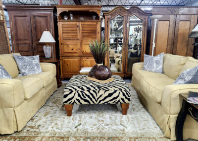 Beige sofas flanking zebra ottoman and wooden armoires