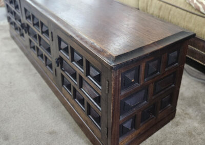 Dark wooden storage bench with carved square panels