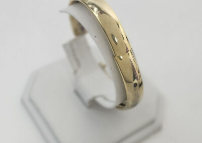 polished gold wedding band on white stand