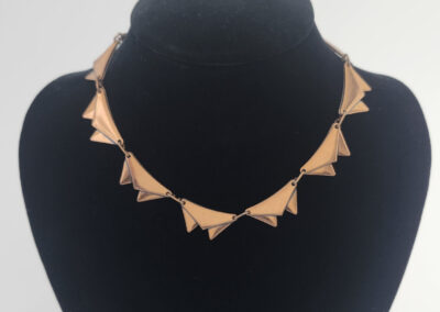 Gold geometric triangular necklace on black bust