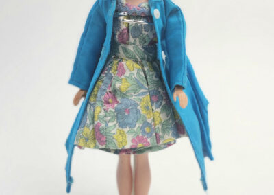 Vintage doll in floral dress and blue coat