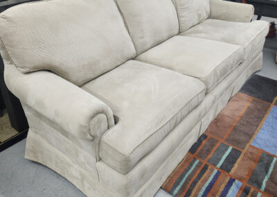 Beige three-seater skirted sofa in showroom