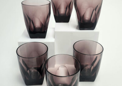 Six smoky purple glass tumblers on white blocks
