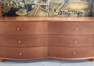 Curved six-drawer wooden dresser with metal knobs