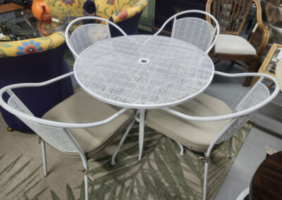 White metal patio table with four cushioned chairs