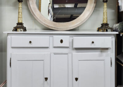 White sideboard with round mirror and lamps