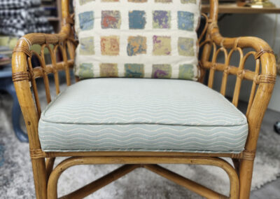 Rattan chair with striped seat cushion, patterned pillow