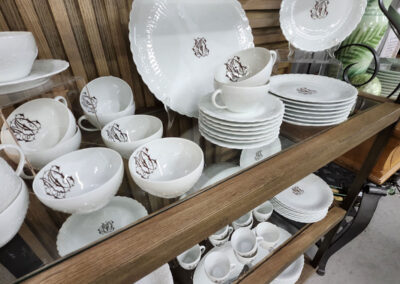 White monogrammed dinnerware set on wooden shelf