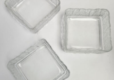 Three clear square glass dishes with wavy rims