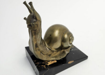 Brass snail sculpture on black marble base